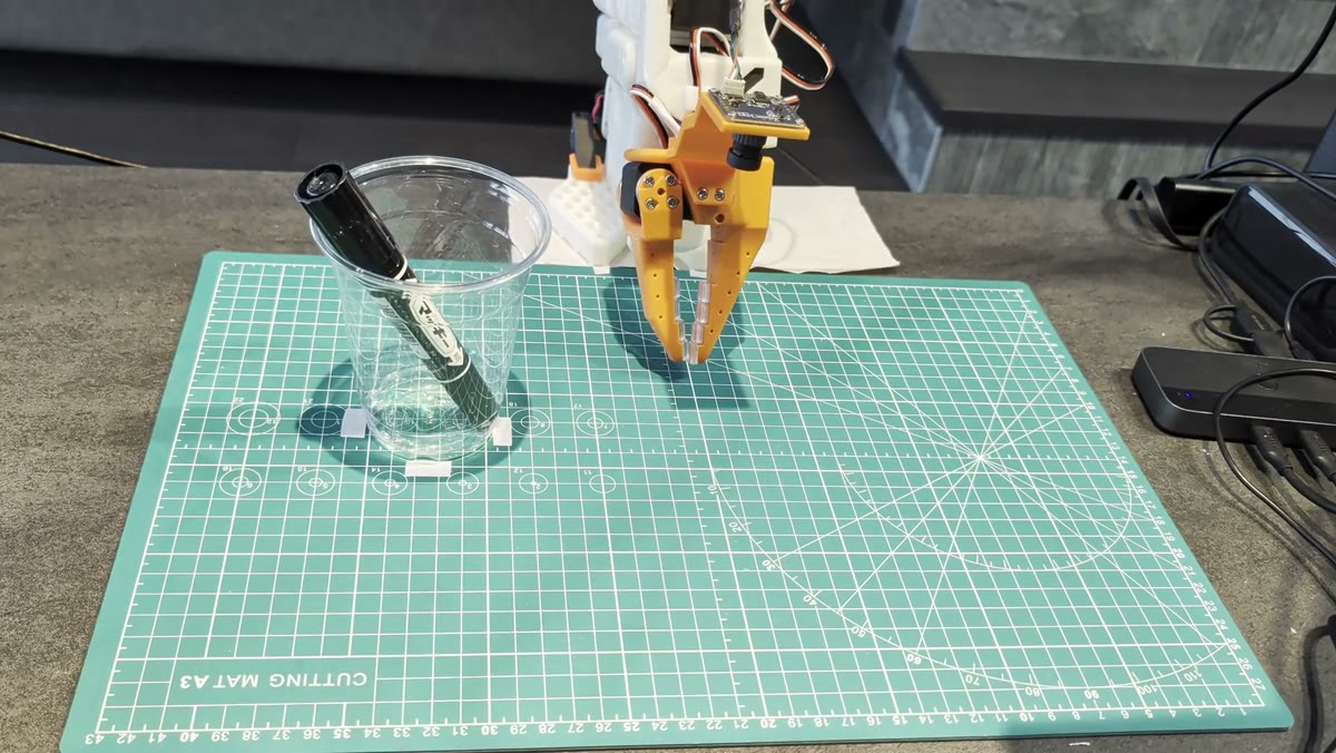 しまってAIのアームがマーカーをコップへ片付ける実写